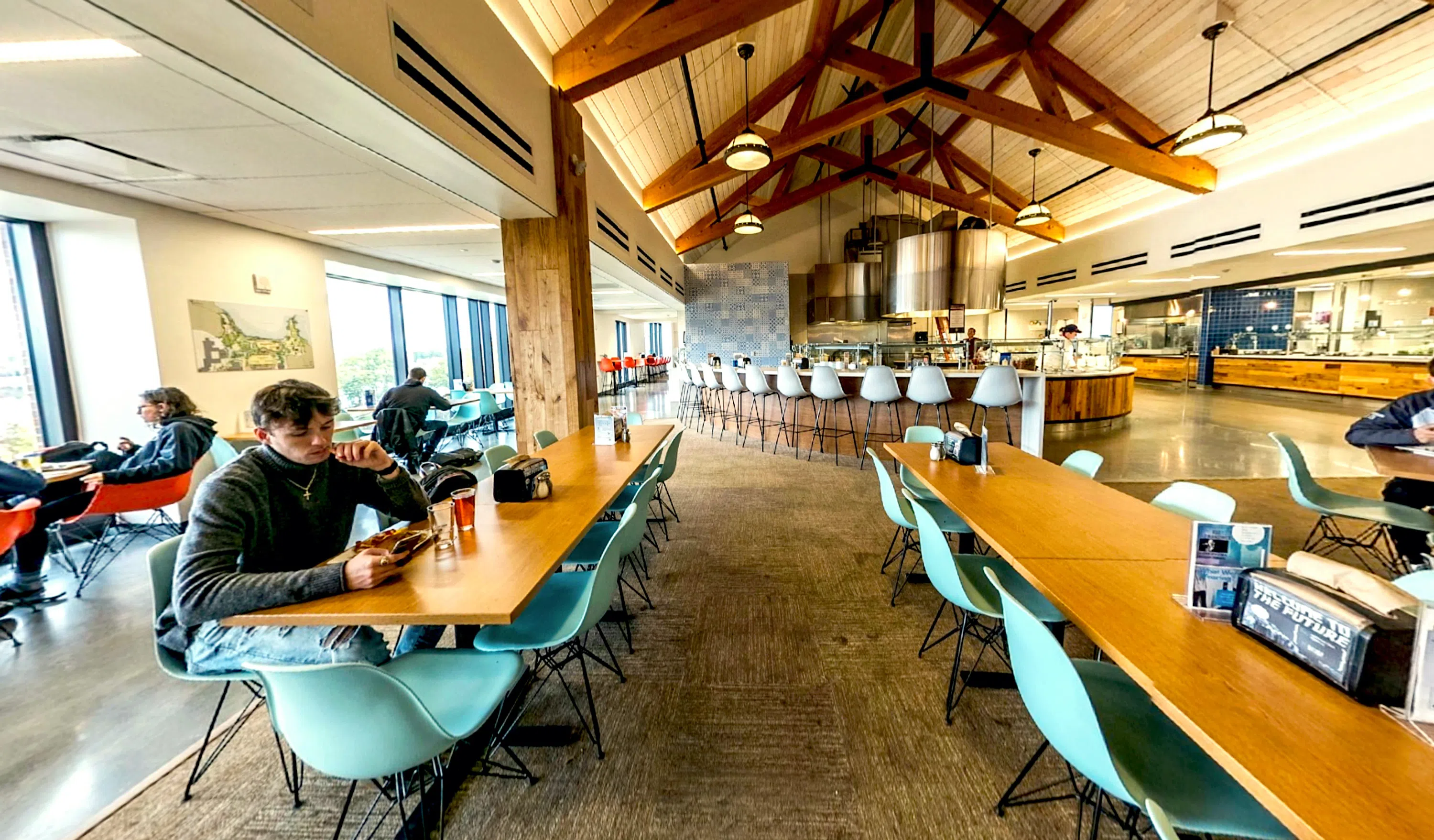 large spacious room with many tables and chairs. students eating