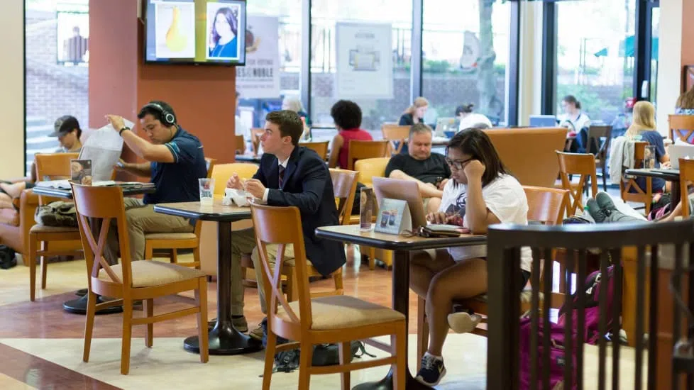 Students sitting at individual tables near the bookstore and the Starbucks