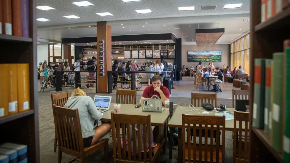 Students wait in line for the Starbucks on the main floor of Thomas Cooper Library as others sit nearby studying.