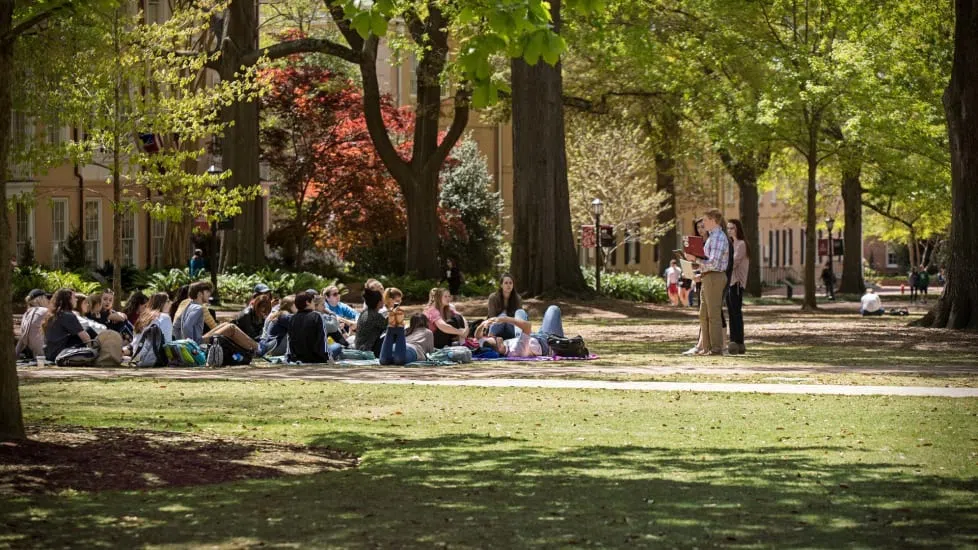 A professor lectures to a group of students while sitting on the Horseshoe