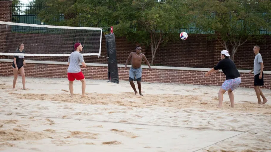 Students play sand volleyball together outside the Strom.