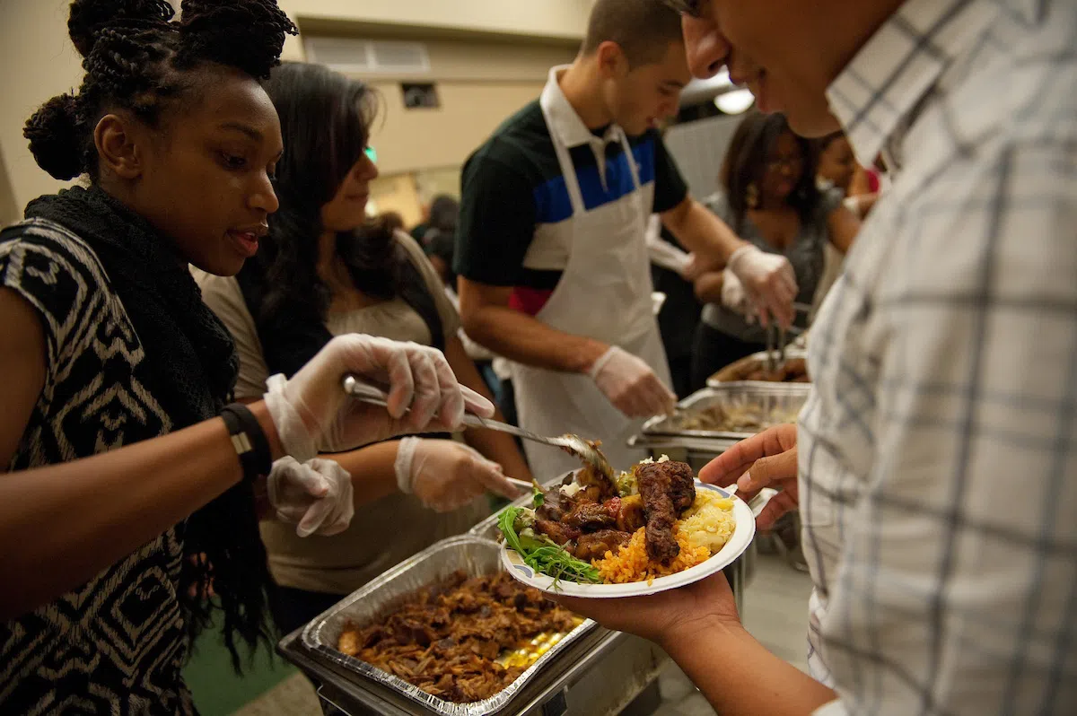A student adding food to a plate in a serving line.