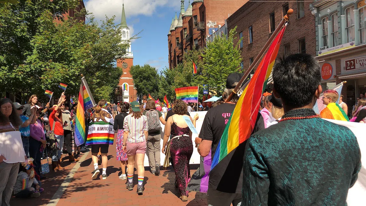 A crowd parading down Church Street with Pride flags.