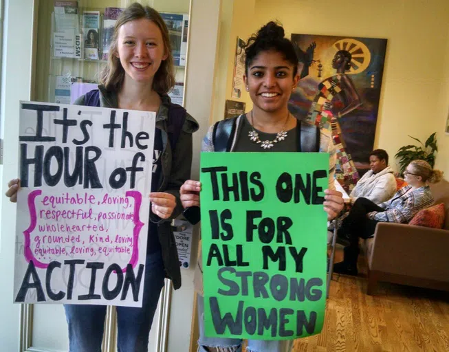 Two Vanderbilt students show signs reading "It's the hour of action" and "This one is for all my strong women."