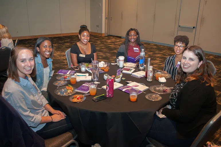 A group of students sit at a table together for the Prevail program