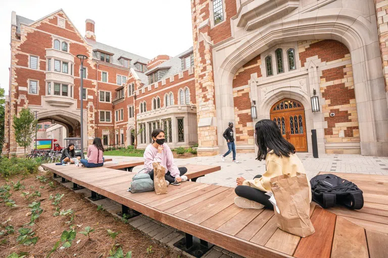 students sit and eat lunch on benches outside of Zeppos College in the West End Neighborhood