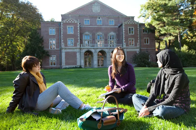 Wellesley students sitting on the lawn outside of Diana Chapman Walsh Alumnae Hall